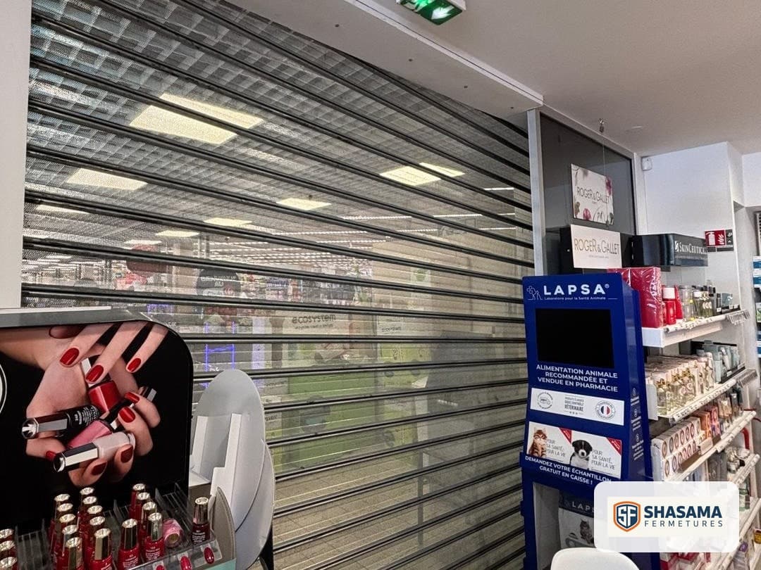 Rideau métallique microperforé fermé sur toute la largeur de la devanture, vu de l’intérieur du commerce