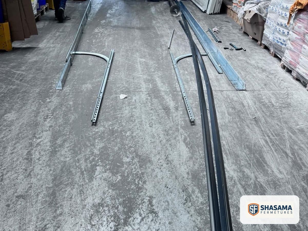 New tracks for an industrial sectional door laid out on the warehouse floor before installation
