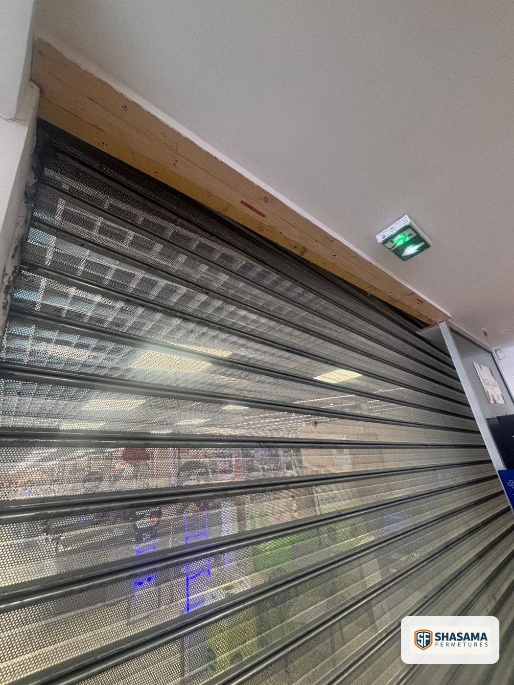 Tablier de rideau métallique à lames perforées, vue rapprochée depuis l’intérieur