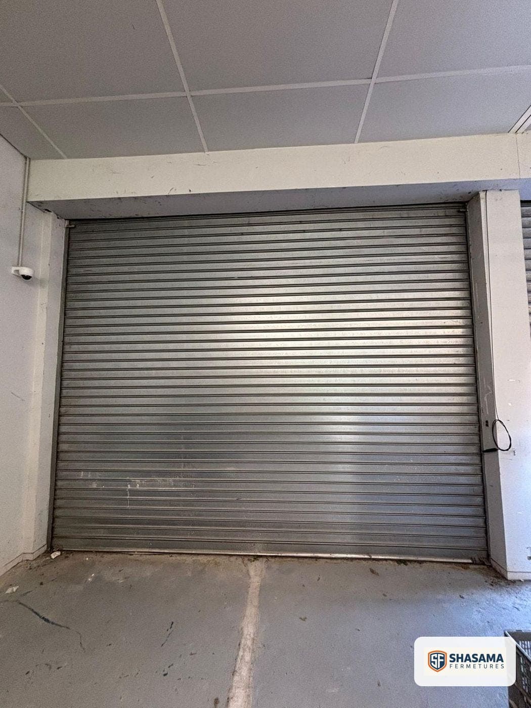 Rideau métallique fermé dans un garage, caméra de surveillance au plafond