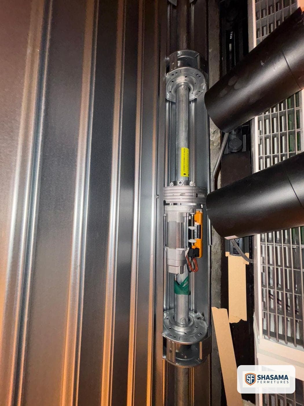 Gros plan sur un moteur tubulaire de rideau métallique et son câblage