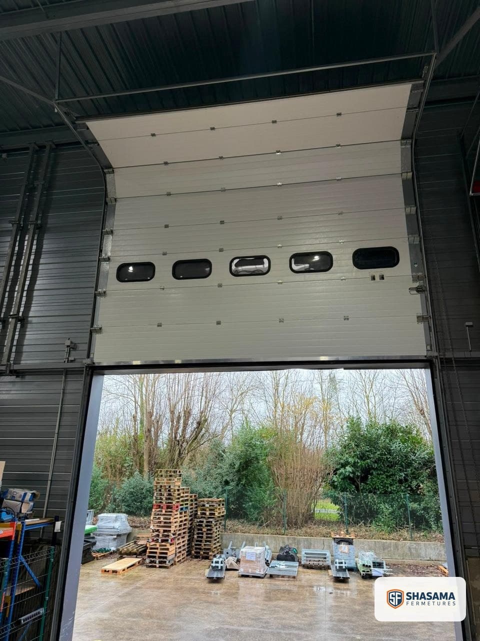 Repair and replacement of panels and cables on an industrial sectional door, partly raised during the opening test