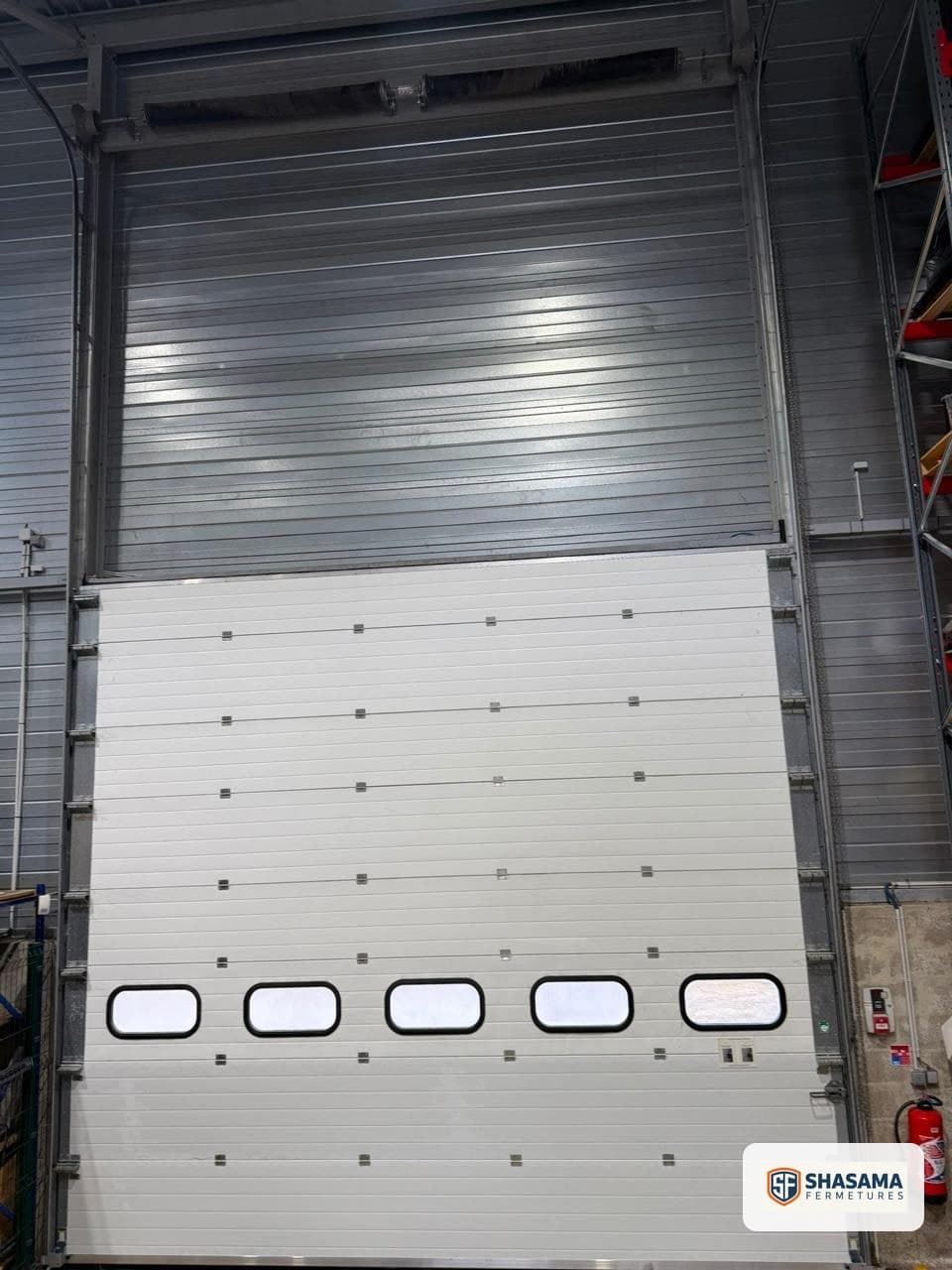 New lower panels on the windowed industrial sectional door, viewed from inside after repair