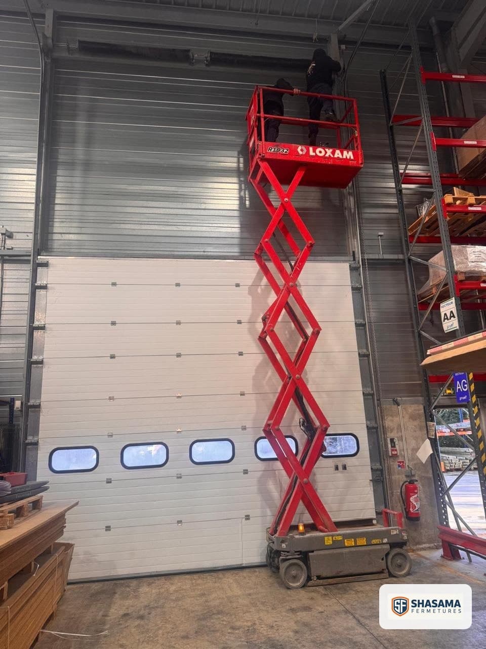 Repair and replacement of panels and cables on an industrial sectional door, with technicians on a lift