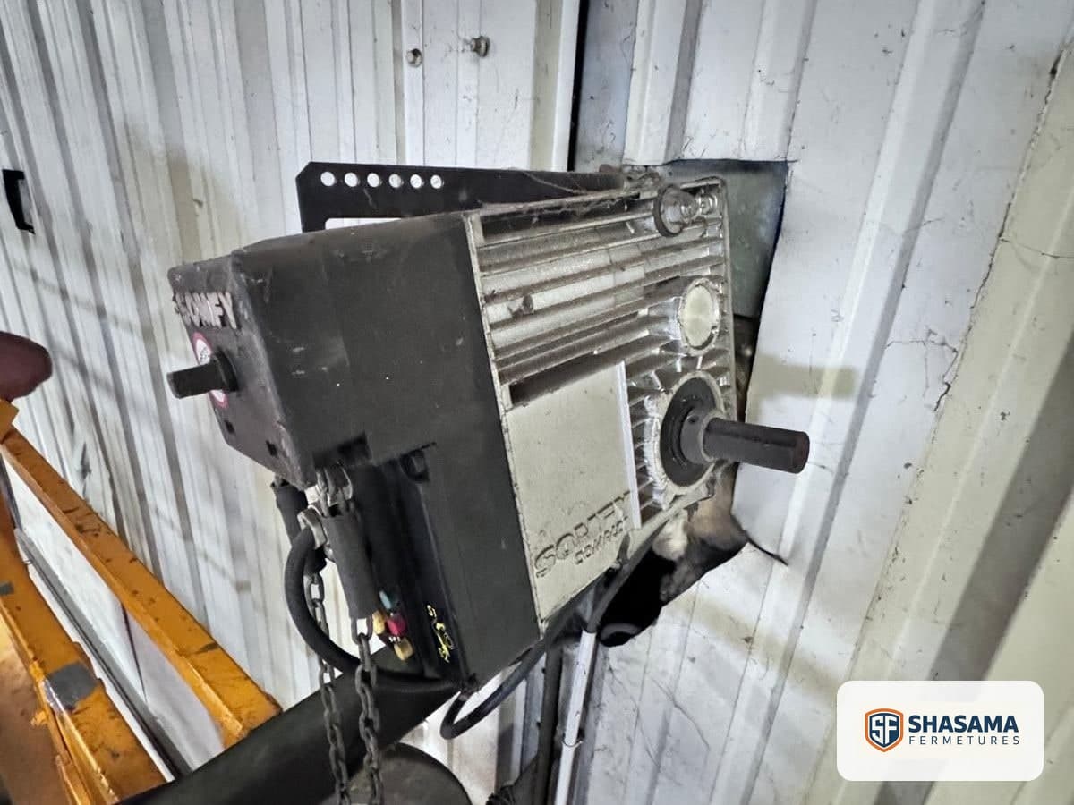Industrial sectional door motor fixed to its metal mounting bracket above the opening