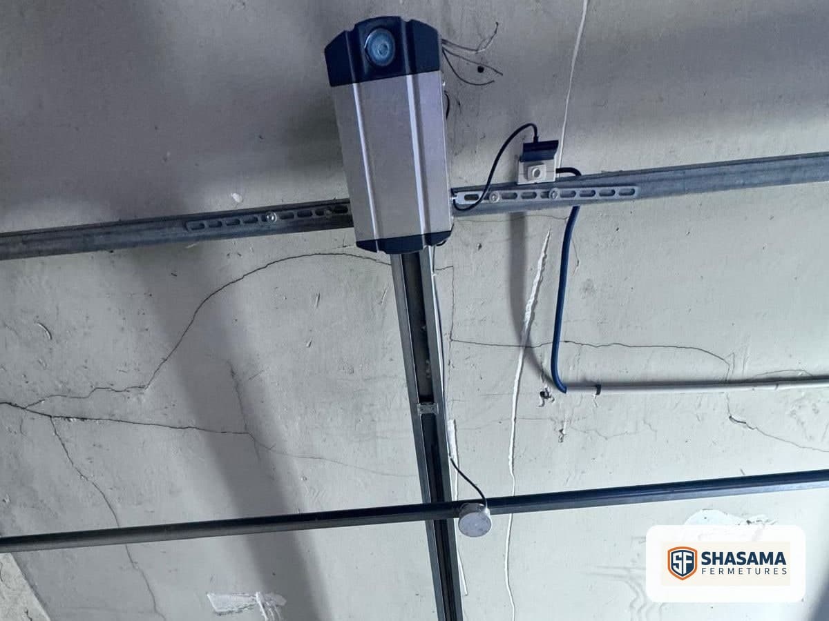 Sectional garage door motor and drive rail fixed to the ceiling, seen from inside the garage