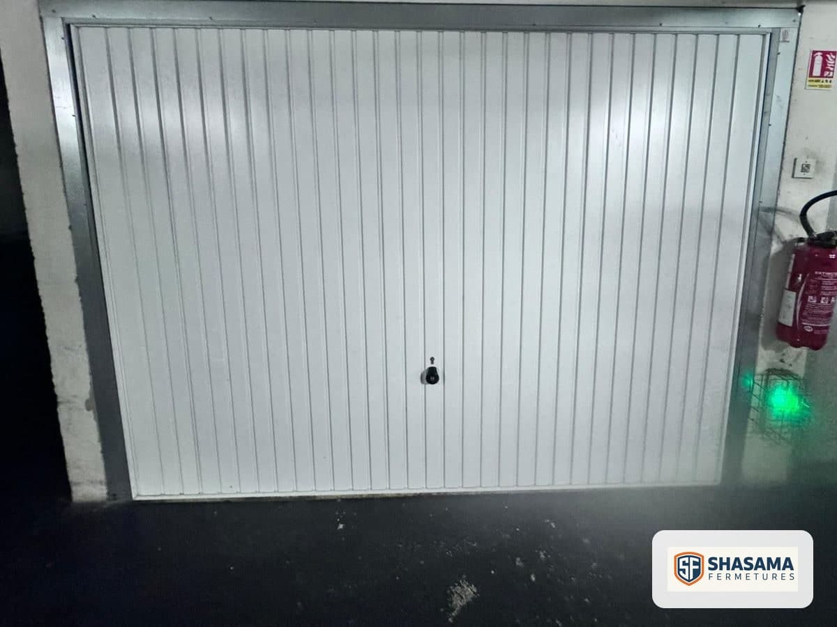 White garage door with vertical ribs, closed within its frame and seen from outside the garage