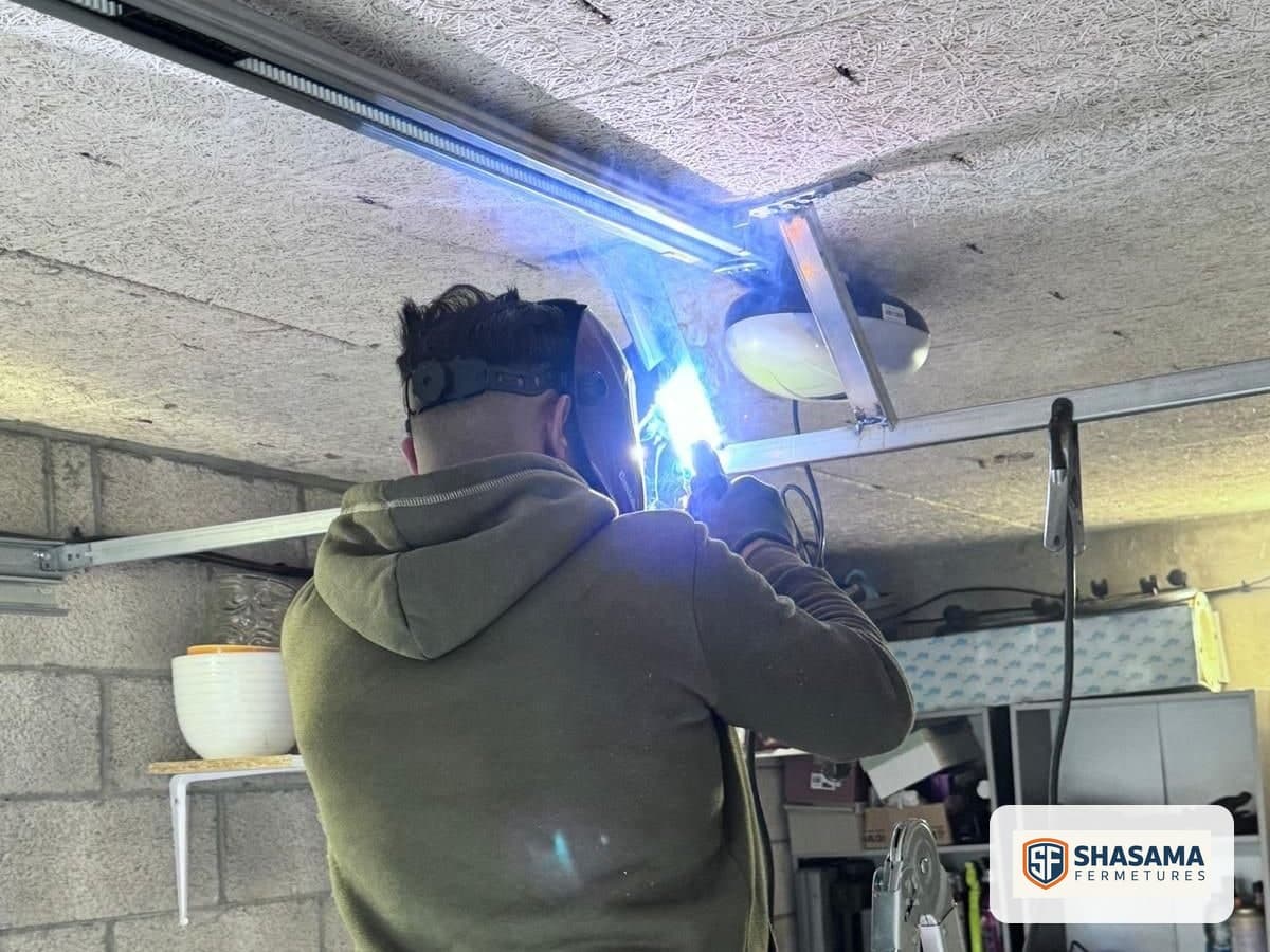 Welding the sectional garage door rail bracket beside the motor fitted to the garage ceiling