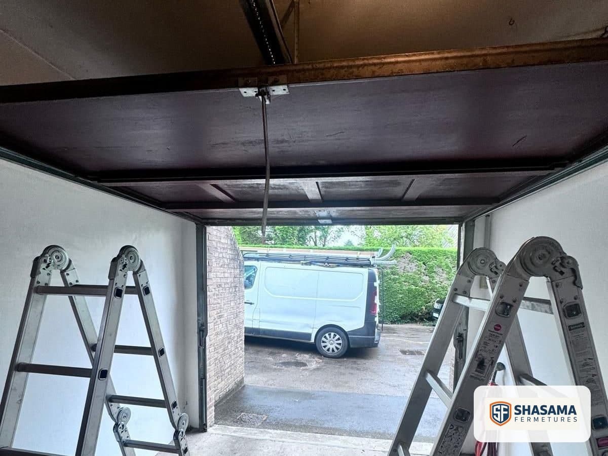 Old wooden up-and-over garage door raised beneath the ceiling before replacement