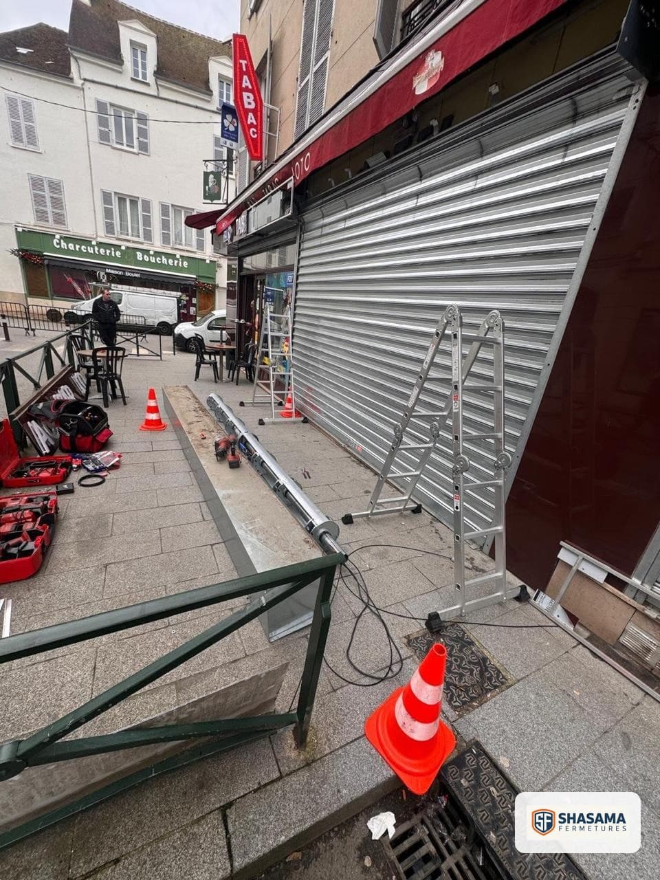 Ancien axe déposé sur le trottoir et nouvel axe tubulaire préparé devant la devanture